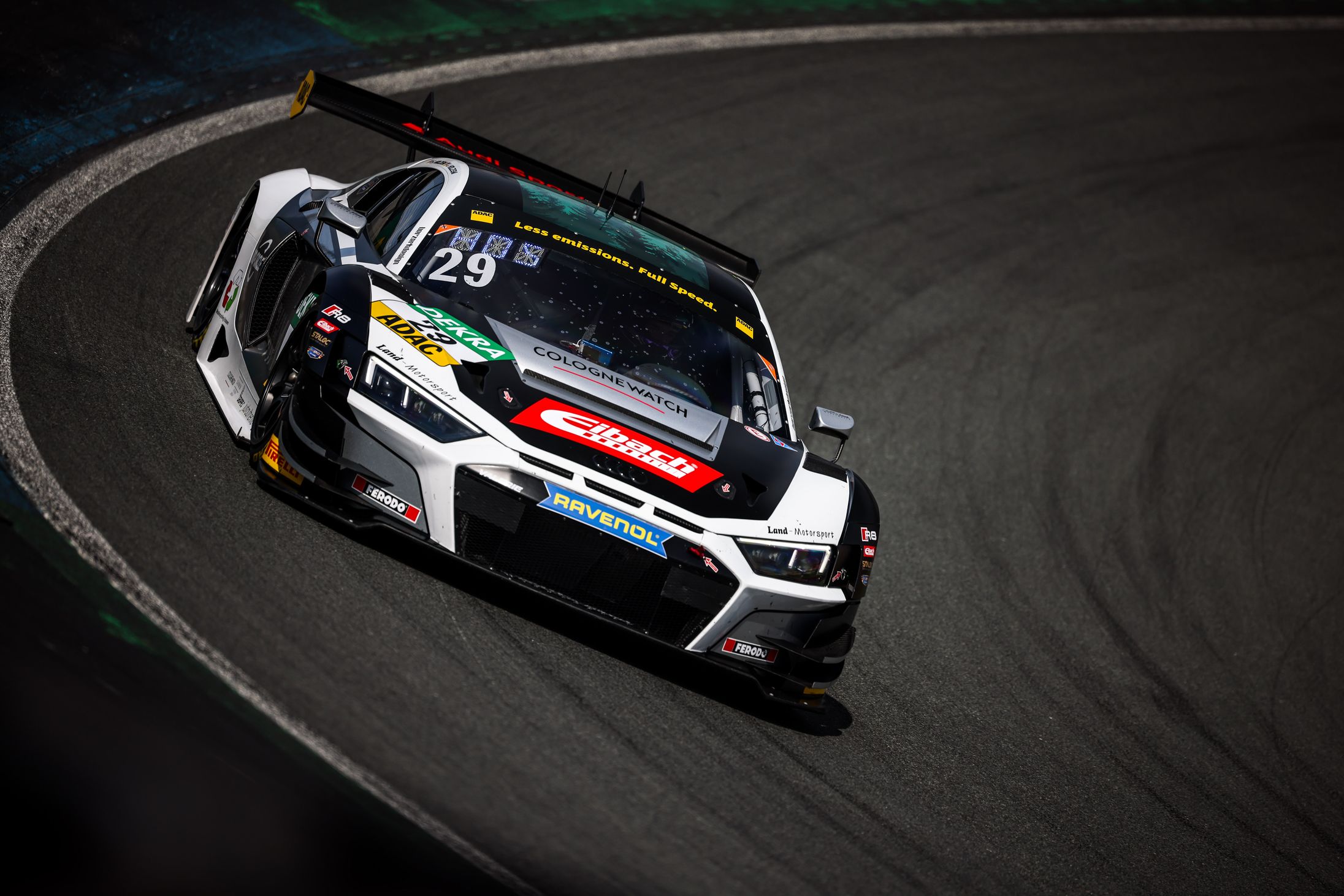 Ein schwarz-weißer Rennwagen mit der Startnummer 29 rast über eine kurvige Rennstrecke. Das Auto ist mit verschiedenen Sponsorenlogos und einem markanten Heckflügel versehen. Das Bild fängt Bewegung und Intensität ein, während der Wagen die Ideallinie entlangfährt.